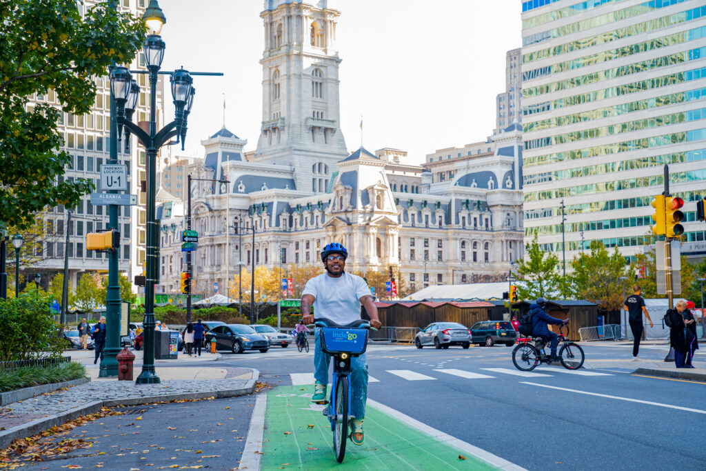 Man riding Indego with City Hall in the background