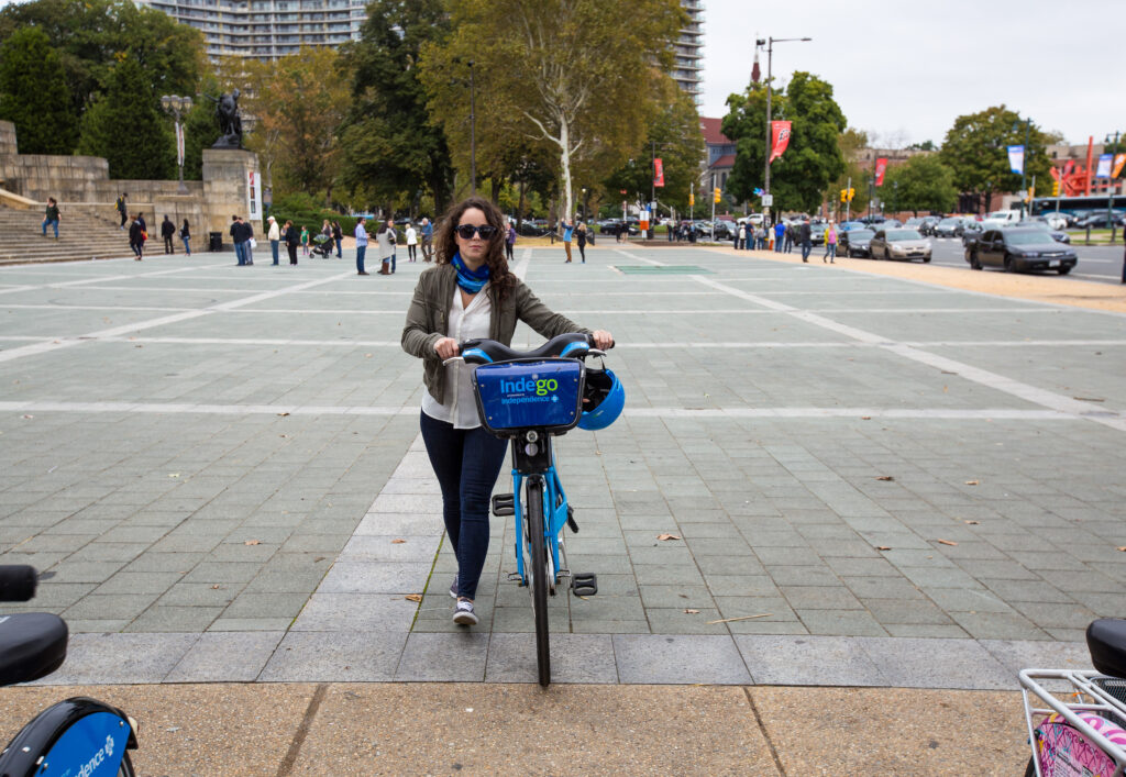Woman docking an Indego bike at the Philadelphia Museum of Art station.