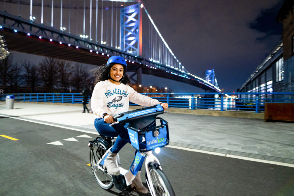 Woman riding Indego near the Ben Franklin Bridge